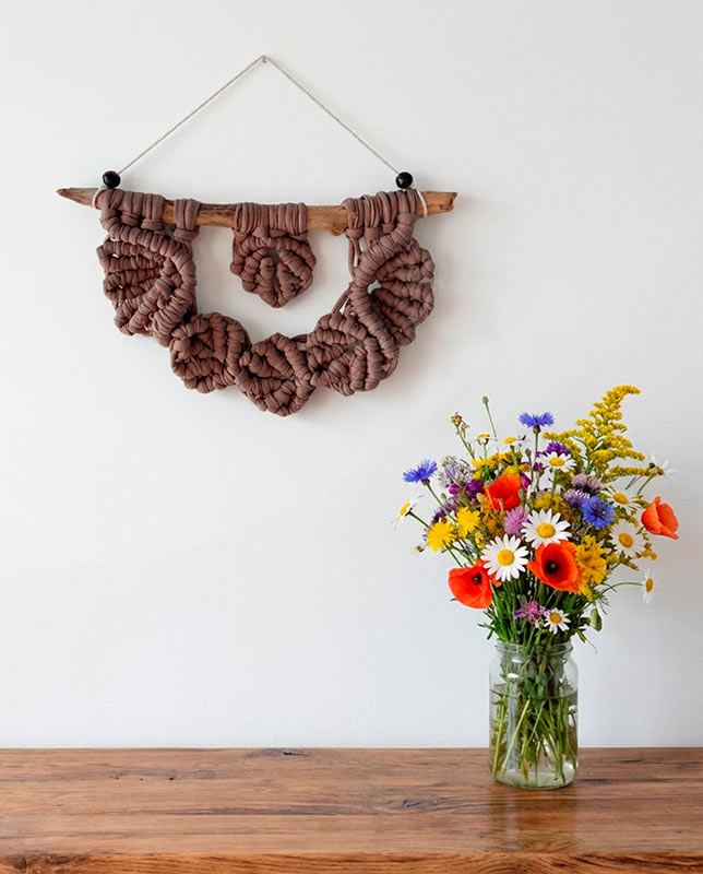 789 Macramé pequeño con hojas tejidas en color marrón suave sobre madera.