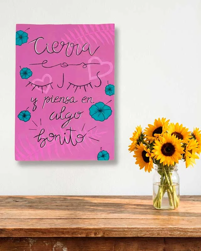 Letrero rosa pintado a mano con la frase "Cierra los ojos y piensa en algo bonito".