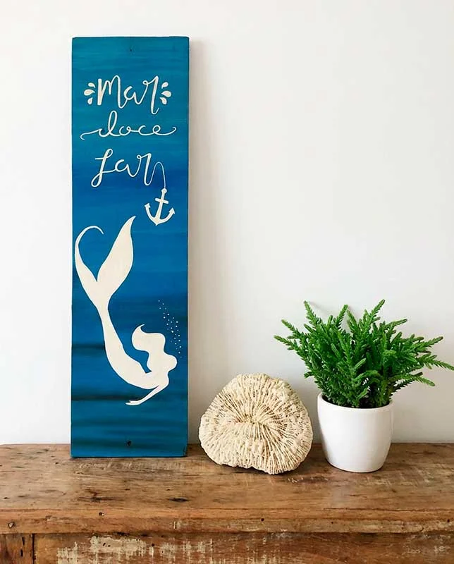 Letrero azul vertical con silueta de sirena y texto "Mar doce lar".