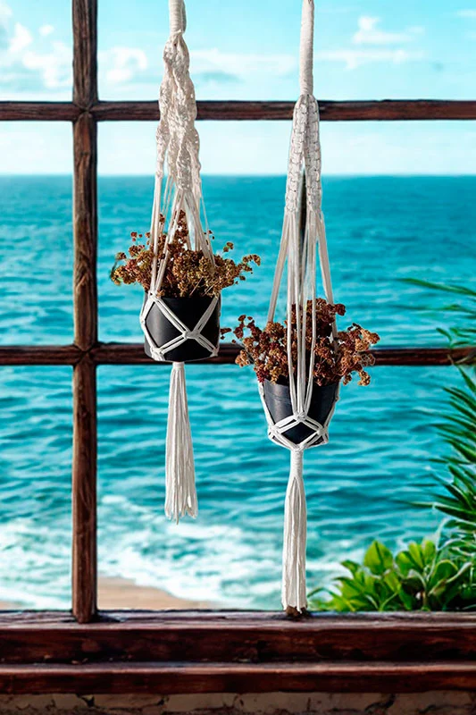 colgador-plantas-macrame-blanco-ventana Pareja de colgadores de macramé blanco para macetas pequeñas frente a una ventana con vistas al mar.