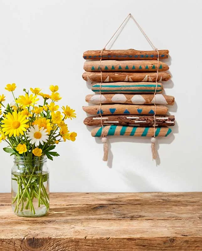 Tapiz horizontal compuesto por pequeñas ramas de madera varada en tonos neutros y verdes.