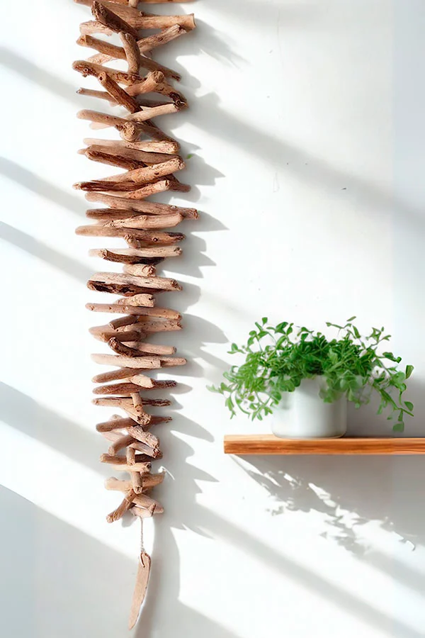 guirnalda-vertical-madera-varada Guirnalda vertical de maderas varadas en tonos claros con una corteza de árbol.