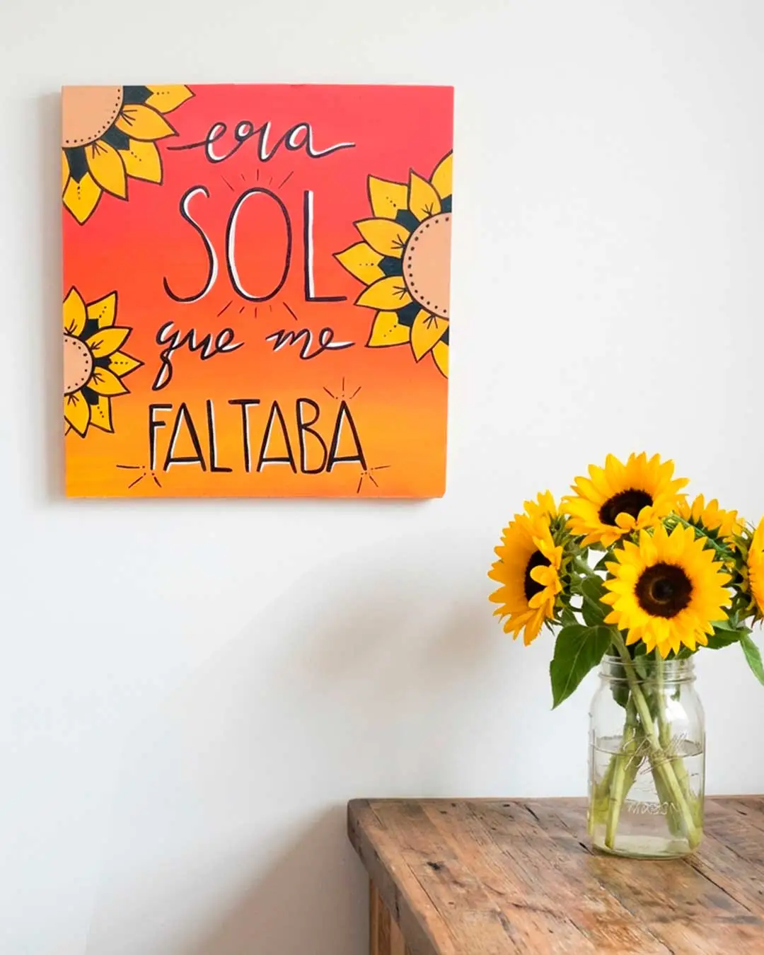 Letrero naranja con girasoles y frase "Era sol que me faltaba" pintado a mano.
