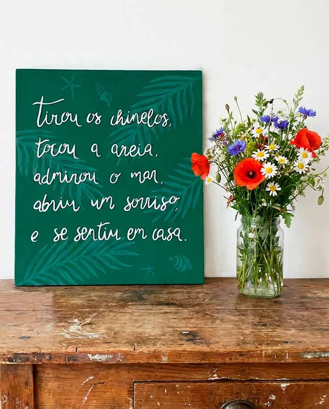 Letrero verde con frase en portugués que evoca la sensación de llegar a la playa.