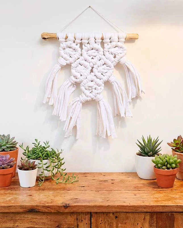 Tapiz de macramé blanco con nudos en relieve y terminaciones en flecos.