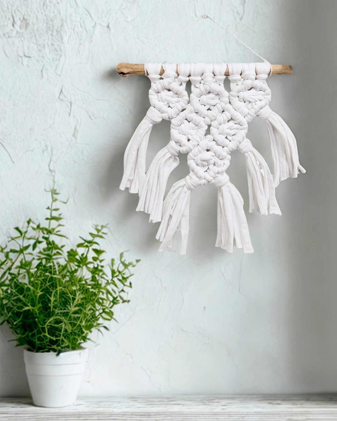 mini-macrame-blanco-geometrico Tapiz de macramé blanco con nudos en relieve y terminaciones en flecos.