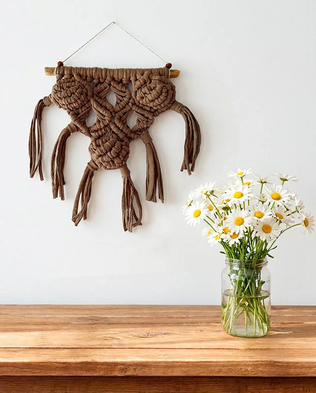 mini-macrame-nudos-relieve-pared Tapiz pequeño en color taupe con nudos voluminosos y flecos laterales.