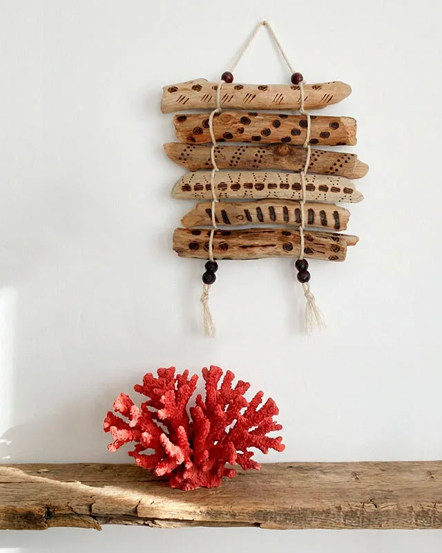 Un tapiz de pared rústico hecho con troncos de madera varada quemados con patrones geométricos étnicos,