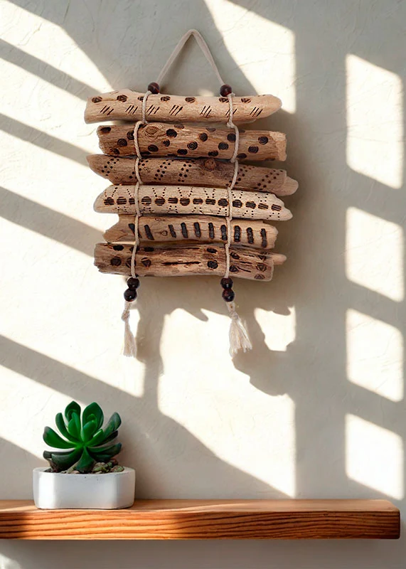 tapiz-ramas-madera-pirografia Composición horizontal de pequeñas ramas de madera varada decoradas con pirografía.